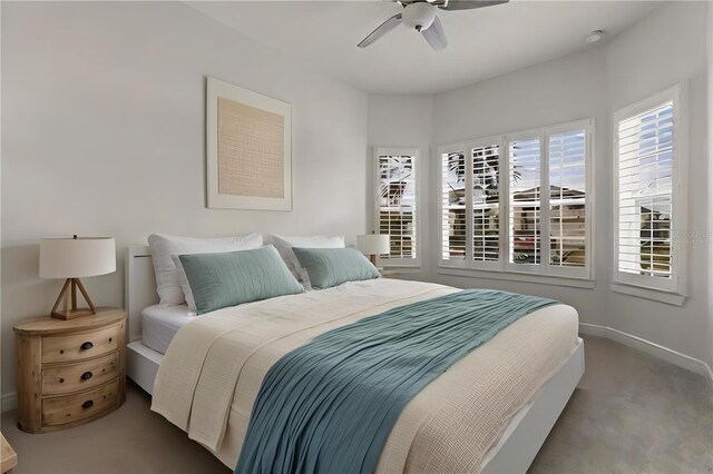 carpeted bedroom with ceiling fan and baseboards