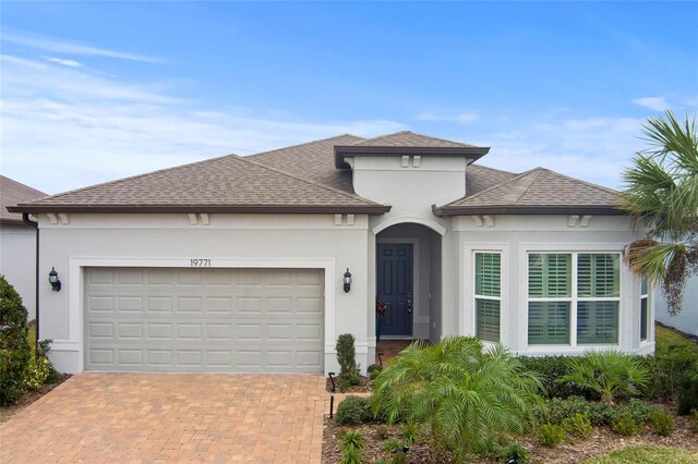 view of front of home featuring a garage, a shingled roof, decorative driveway, and stucco siding