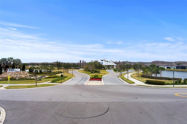 view of road with curbs, a water view, and sidewalks