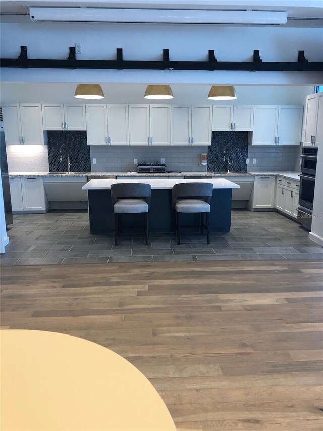 kitchen with tasteful backsplash, a center island, light countertops, and multiple ovens