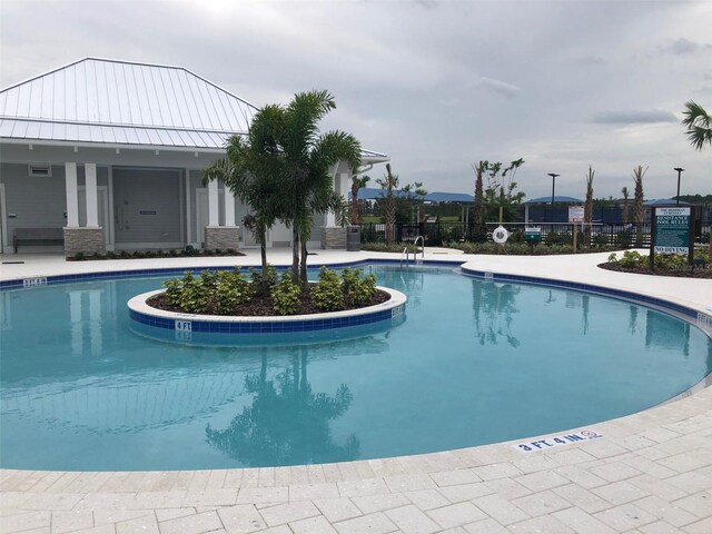 community pool with a patio area and fence