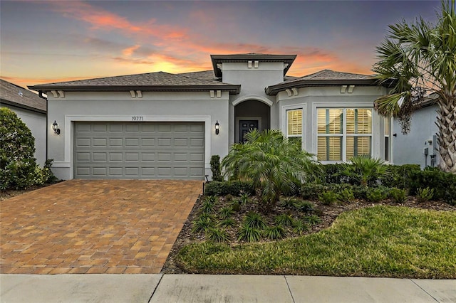 view of front of house with a garage, decorative driveway, and stucco siding