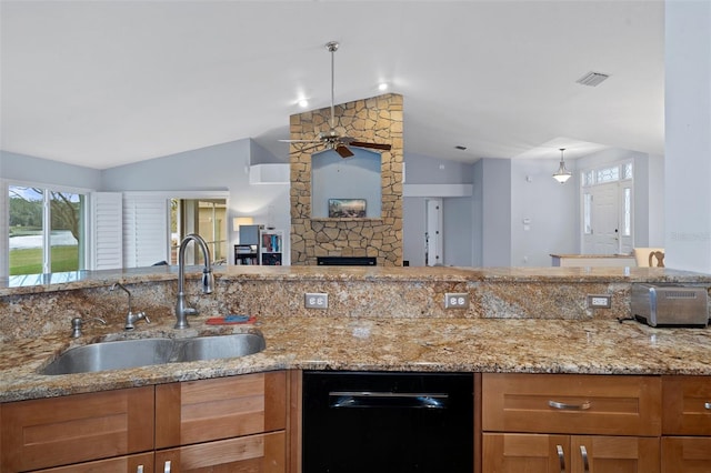 kitchen featuring sink, black dishwasher, light stone counters, lofted ceiling, and a stone fireplace