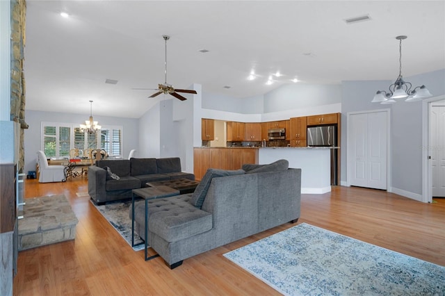 living room featuring ceiling fan with notable chandelier, high vaulted ceiling, and light wood-type flooring