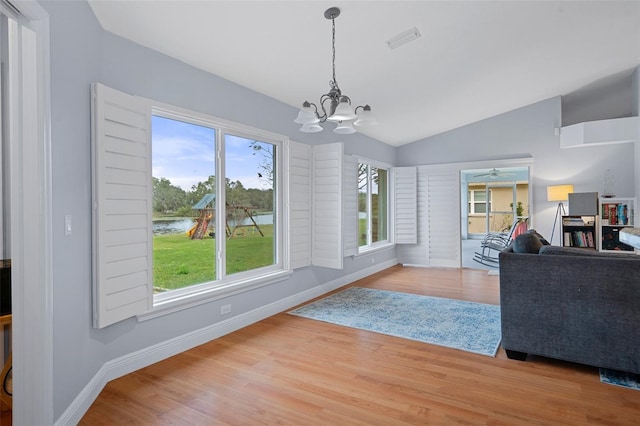 interior space featuring ceiling fan with notable chandelier, light wood-type flooring, lofted ceiling, and plenty of natural light