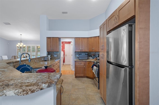 kitchen featuring decorative light fixtures, stainless steel appliances, kitchen peninsula, an inviting chandelier, and backsplash