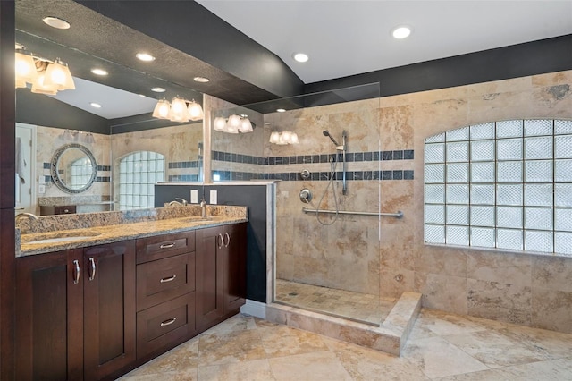 bathroom with a tile shower, vanity, and vaulted ceiling