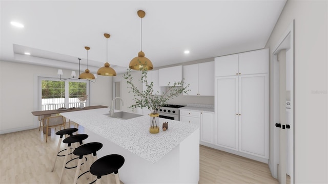 kitchen featuring hanging light fixtures, an island with sink, range with gas stovetop, white cabinets, and sink