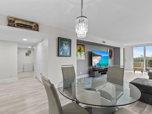 dining space featuring light hardwood / wood-style floors, expansive windows, and a notable chandelier