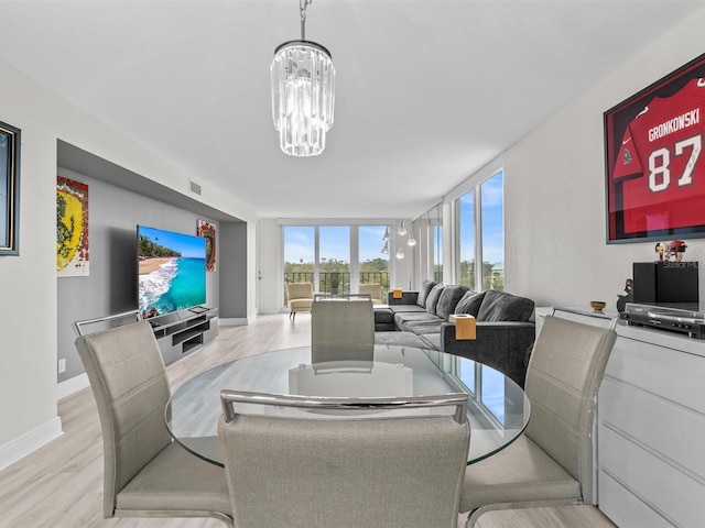 dining room with light hardwood / wood-style floors, floor to ceiling windows, and a notable chandelier