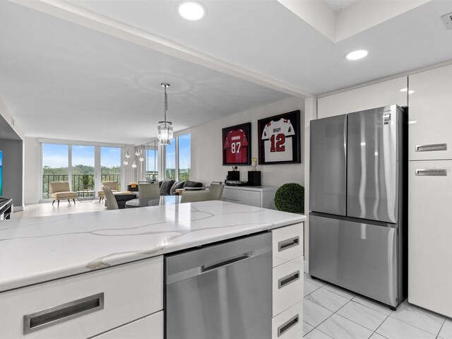 kitchen featuring light stone countertops, stainless steel appliances, white cabinets, and decorative light fixtures