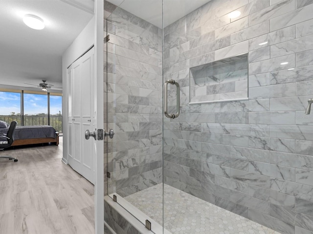 bathroom with ceiling fan, a shower with shower door, and hardwood / wood-style floors