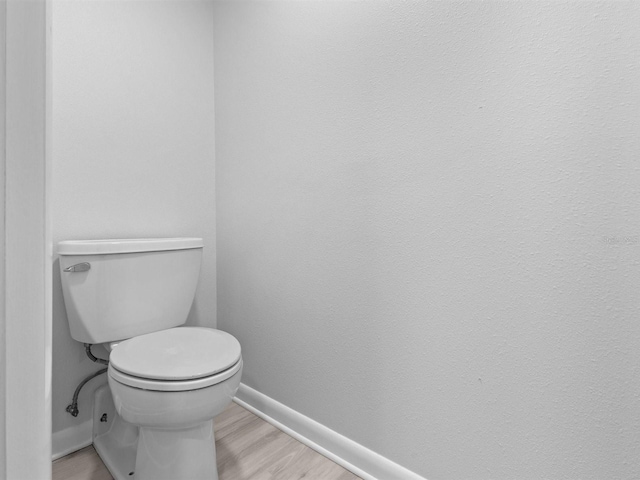 bathroom with hardwood / wood-style floors and toilet