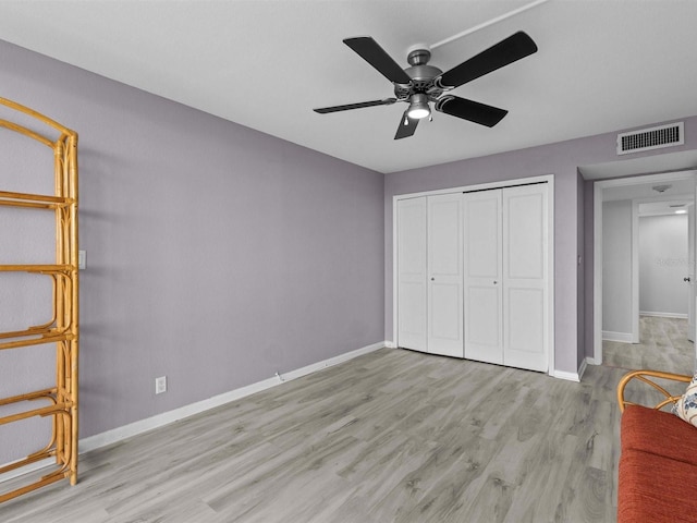 unfurnished bedroom featuring ceiling fan, a closet, and light wood-type flooring