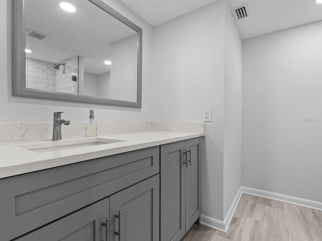 bathroom with walk in shower, vanity, and hardwood / wood-style flooring