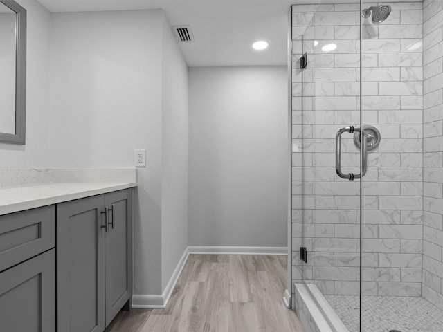 bathroom with wood-type flooring, a shower with door, and vanity