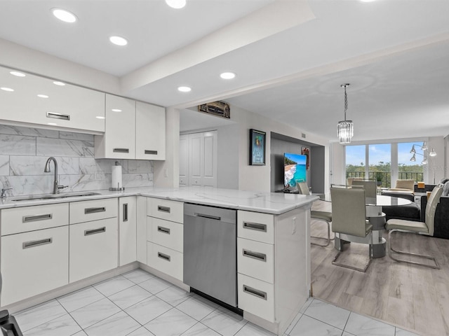 kitchen featuring dishwasher, white cabinetry, decorative backsplash, sink, and kitchen peninsula