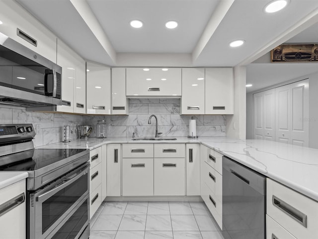 kitchen featuring white cabinets, appliances with stainless steel finishes, tasteful backsplash, sink, and light stone counters