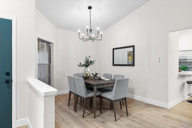 dining room with an inviting chandelier, vaulted ceiling, and light hardwood / wood-style flooring