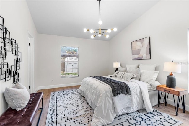 bedroom featuring light hardwood / wood-style flooring, an inviting chandelier, and vaulted ceiling