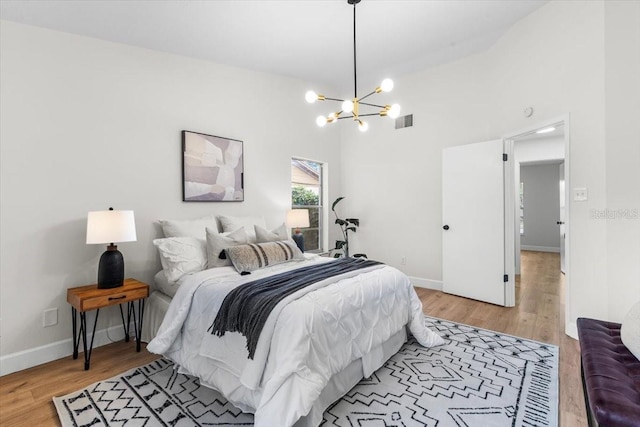 bedroom with an inviting chandelier, high vaulted ceiling, and hardwood / wood-style flooring