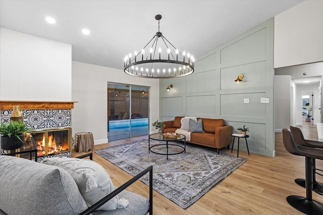 living room featuring a notable chandelier, light hardwood / wood-style flooring, and a tile fireplace