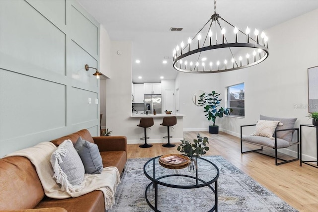 living room with light hardwood / wood-style floors and an inviting chandelier