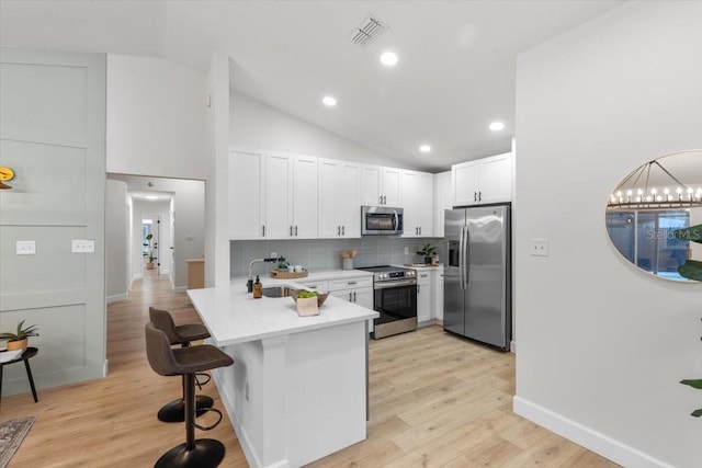 kitchen with sink, stainless steel appliances, vaulted ceiling, and white cabinetry