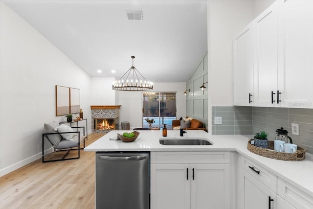 kitchen with white cabinets, stainless steel dishwasher, kitchen peninsula, and sink