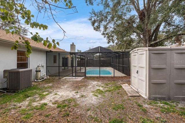 view of yard with central air condition unit, a lanai, a fenced in pool, and a shed