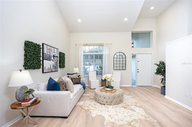 living room featuring a towering ceiling and light hardwood / wood-style floors