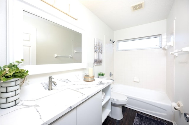 full bathroom with toilet, tiled shower / bath, vanity, hardwood / wood-style flooring, and a textured ceiling