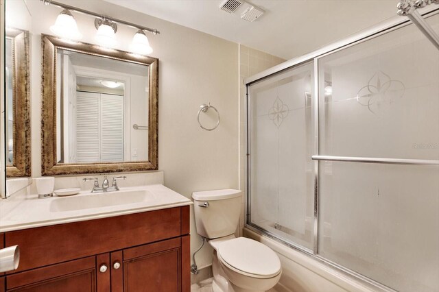 full bathroom featuring toilet, vanity, and shower / bath combination with glass door