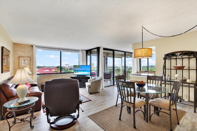 dining area with floor to ceiling windows, a textured ceiling, and light wood-type flooring