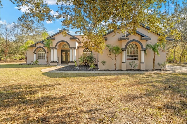 mediterranean / spanish-style house featuring a front lawn and french doors