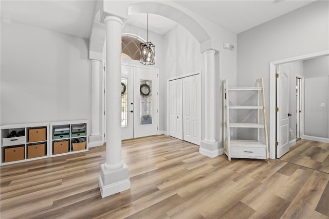 foyer entrance featuring wood-type flooring, an inviting chandelier, and decorative columns