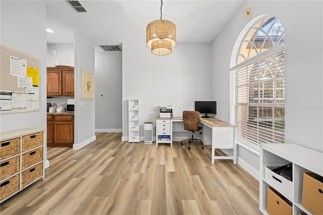 office with light hardwood / wood-style floors, plenty of natural light, and a notable chandelier