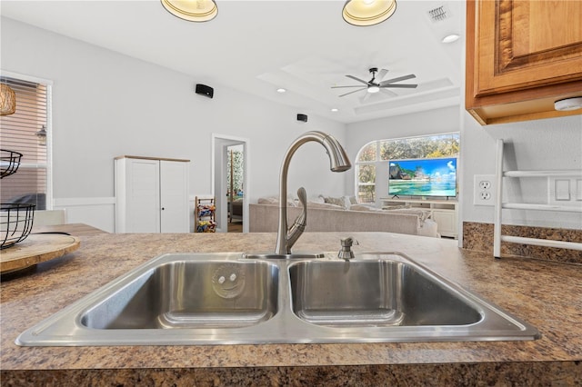 kitchen featuring ceiling fan, sink, and a tray ceiling