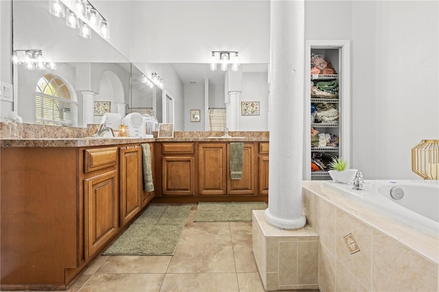 bathroom featuring decorative columns, tiled bath, vanity, and tile patterned flooring