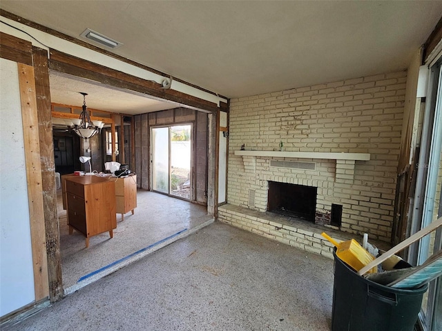 unfurnished living room featuring a fireplace and a chandelier