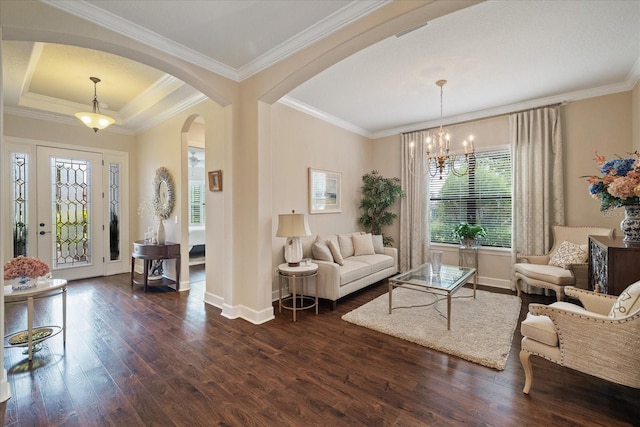 living room with dark wood-type flooring, ornamental molding, and a chandelier