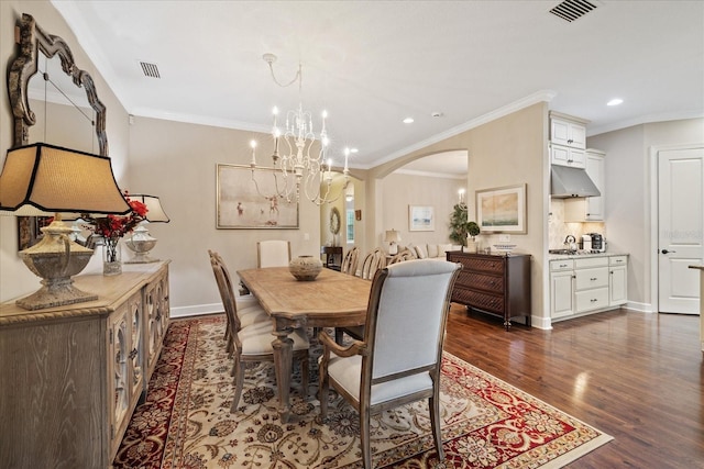 dining area featuring dark hardwood / wood-style flooring, an inviting chandelier, and crown molding