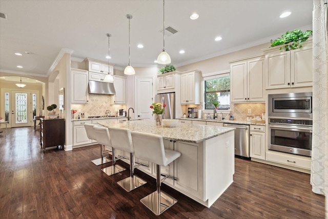 kitchen featuring pendant lighting, decorative backsplash, a kitchen island with sink, appliances with stainless steel finishes, and sink