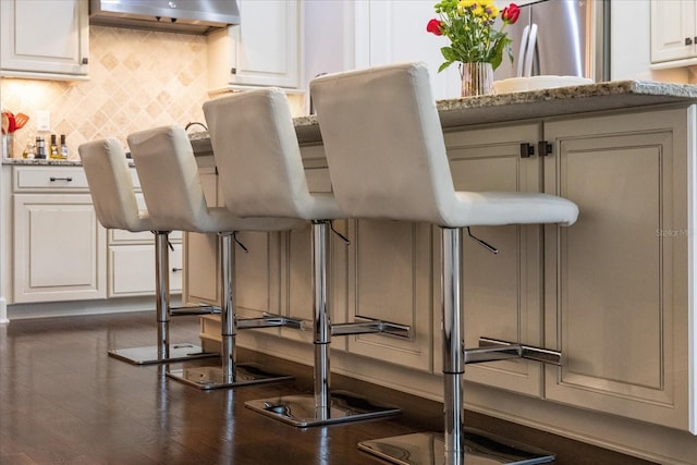 interior space featuring white cabinetry, light stone counters, decorative backsplash, and stainless steel refrigerator