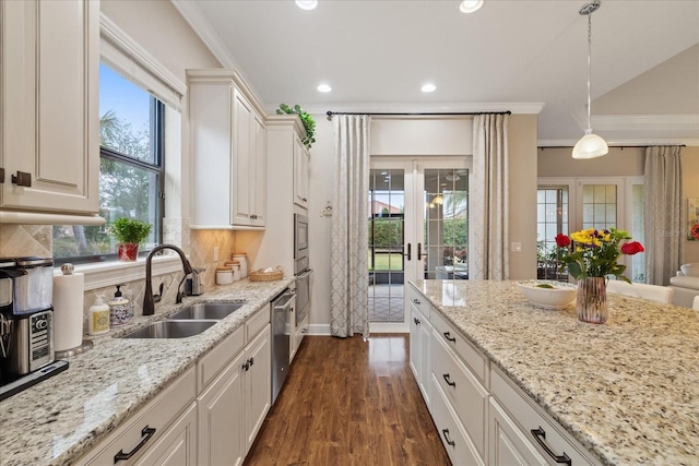 kitchen with white cabinets, appliances with stainless steel finishes, hanging light fixtures, ornamental molding, and sink