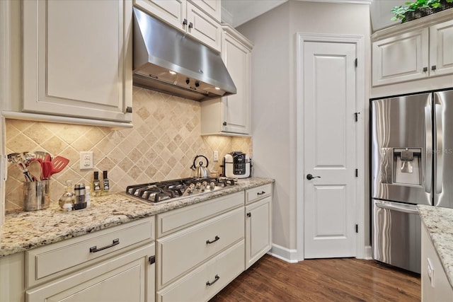 kitchen featuring light stone countertops, dark wood-type flooring, decorative backsplash, white cabinets, and appliances with stainless steel finishes