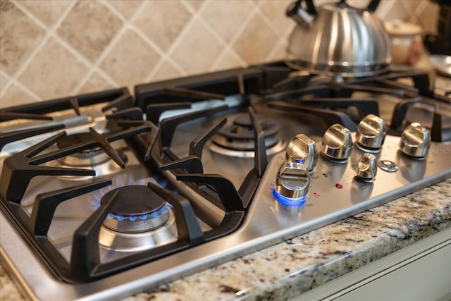 details featuring stainless steel gas stovetop and backsplash