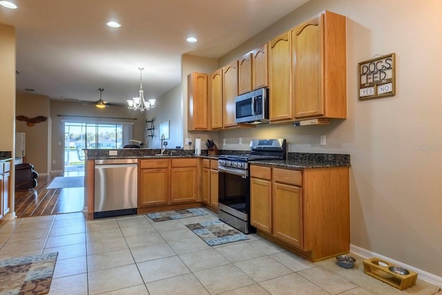 kitchen with stainless steel appliances, hanging light fixtures, kitchen peninsula, light tile patterned flooring, and ceiling fan with notable chandelier