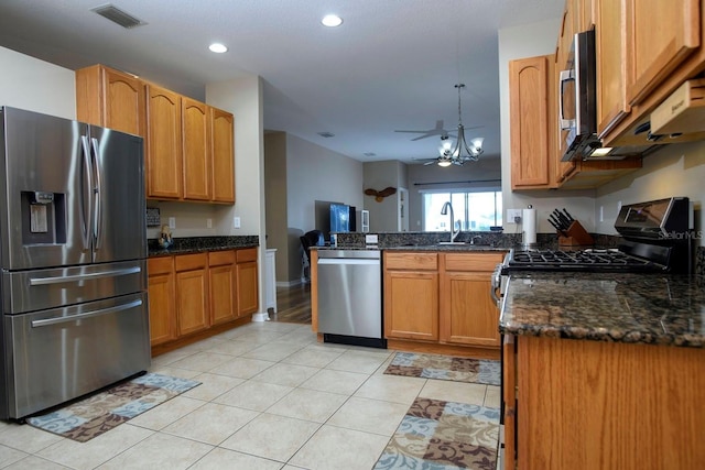 kitchen with stainless steel appliances, dark stone counters, ceiling fan, decorative light fixtures, and light tile patterned flooring