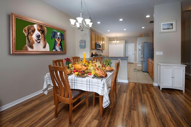 dining space with sink, dark hardwood / wood-style flooring, and an inviting chandelier